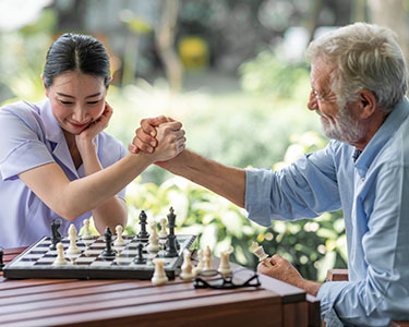 Female playing chess with an older man.