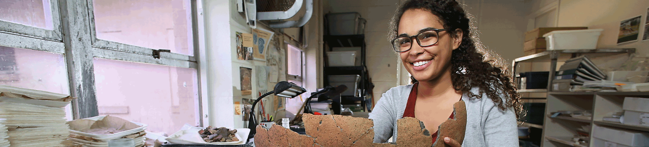 Female student holding an artifact in a lab.