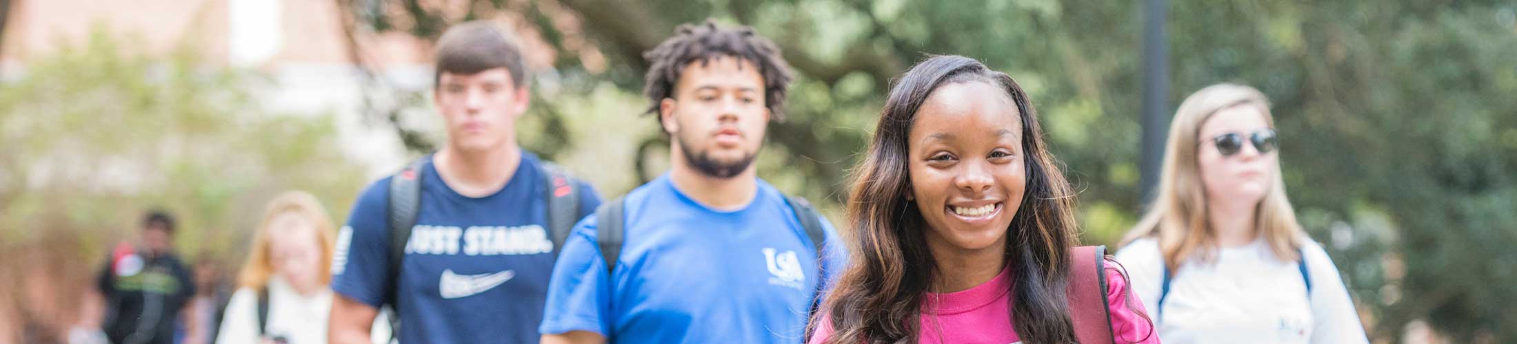 Female student walking on campus smiling.