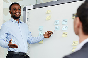 Man at whiteboard teaching to a class.