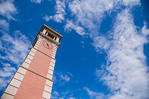 Moulton Tower clock with clouds behind it.