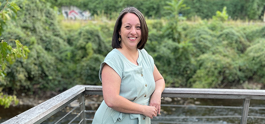 Dr. Jessica Bauer standing outside on bridge over water on campus.