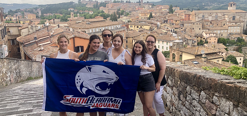 HTM Students in Italy holding Jag flag.