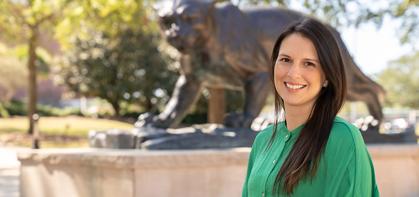 Jennifer Palomo-Gregory in front of jaguar statue on campus.