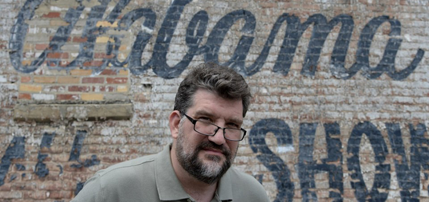 John Archibald standing outside in front of a brick building.