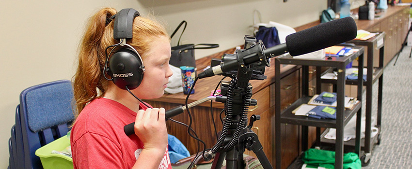 Literacy Summer Camper with headphones on and microphone.