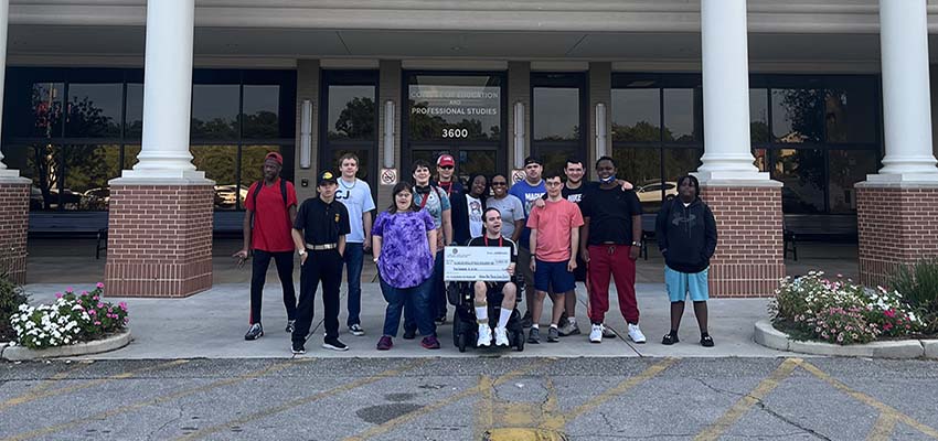 PASSAGE USA students in front of the College of Education holding up their check. data-lightbox='featured'