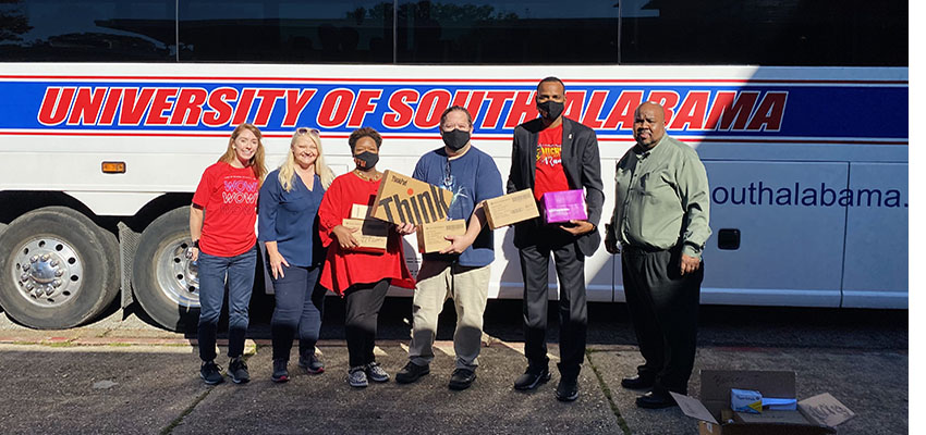 USA Robert Noyce Scholars standing in front of USA bus with classroom materials.