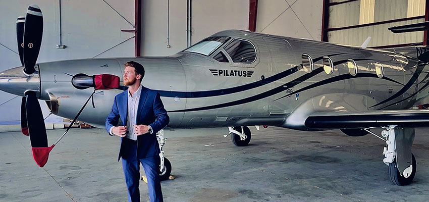 Hospitality Grad -Aaron White standing in front of a plane.