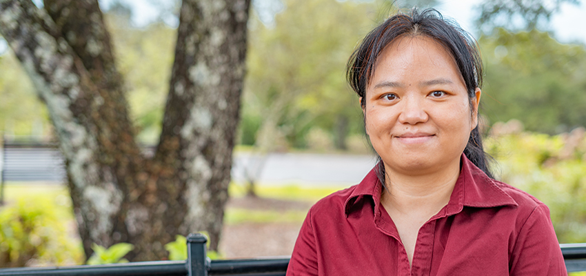 Dr. Shenghua Zha sitting outside on campus on a bench,