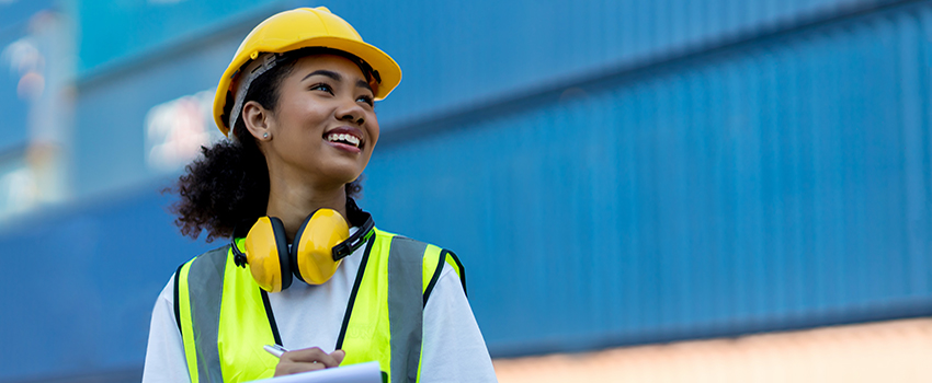 Organizational Leader on job site with hard hat on taking notes.