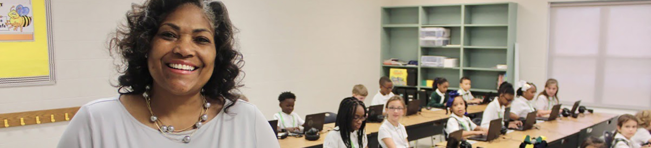 Teacher smiling in front of class of kids.