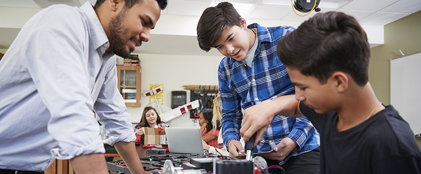 Students building projects in classroom with teacher.