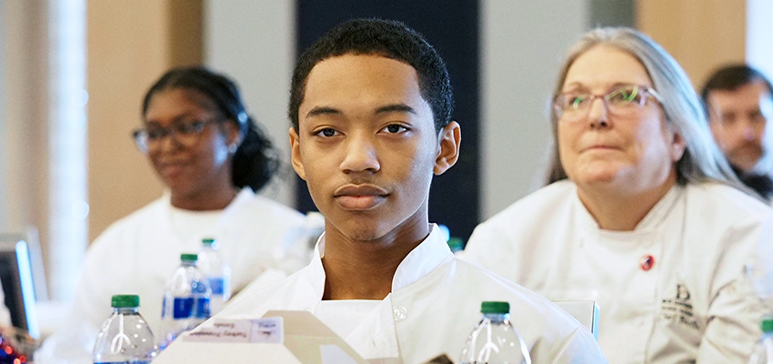 Culinary high school students in shite coats at conference.