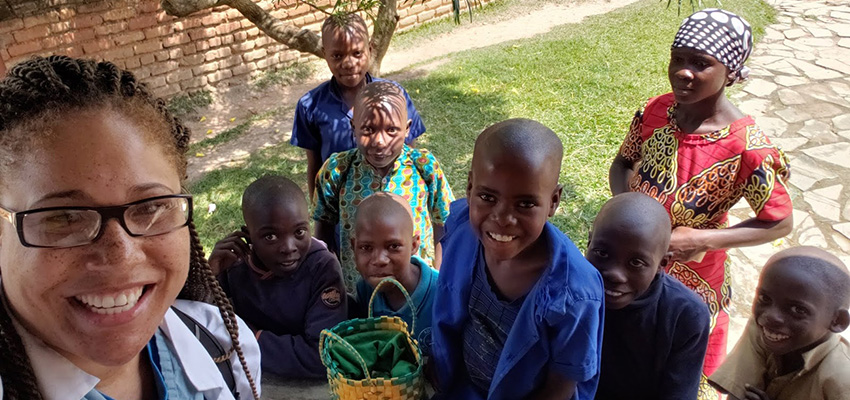 A USA medical student poses with children while on a recent mission trip.