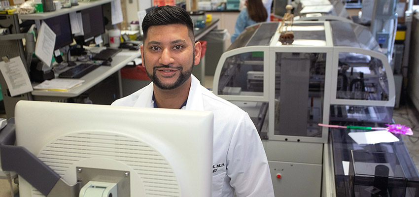 Zan Ahmed, M.D., poses at a computer.