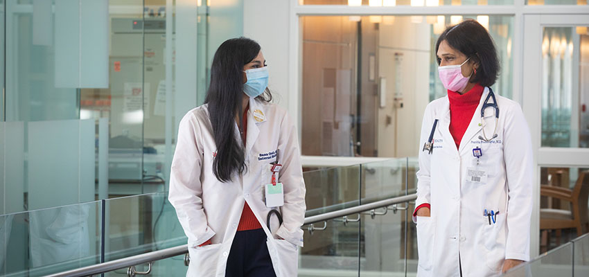 Internal medicine resident Sana Ozair, M.D., talks with Dr. Pranitha Proddutuvar, medical oncologist and assistant professor of interdisciplinary clinical oncology. 