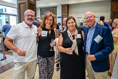 Four alumni smiling at event at alumni center.