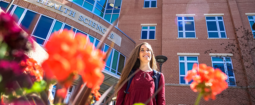 Female Student walking out of Allied Health smiling
