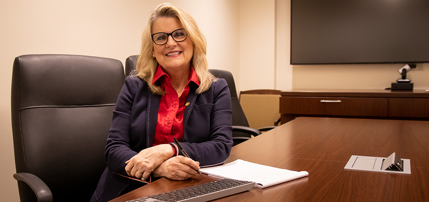 Carolyn Dolan sitting at her desk in the College of Nursing.