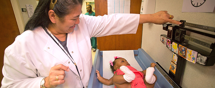 Nurse weighing baby