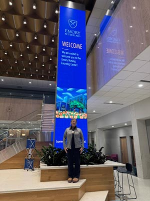 Carol Pierce standing in front of welcome sign 