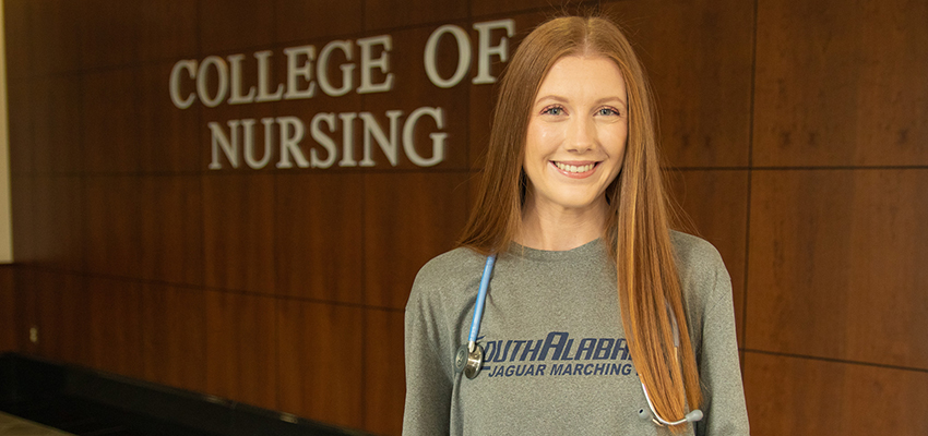 Emily Sims standing in front of College of Nursing sign. data-lightbox='featured'