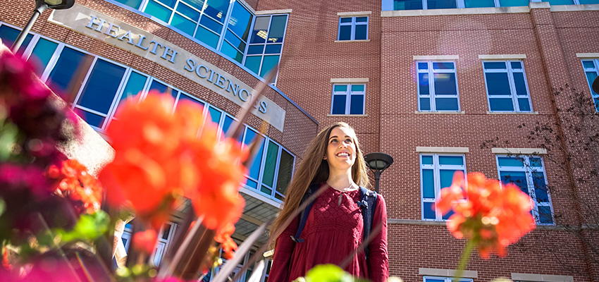 Nursing student smiling outside of the Health Sciences Building.