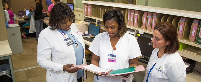 Nurses around desk consulting over a file