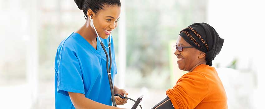 Smiling nurse checking senior patient's blood pressure