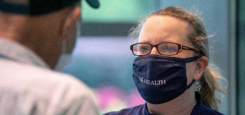 Dr. Minchew with mask on talking to patient.