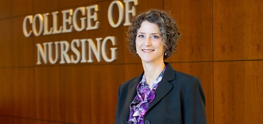 Rebecca Graves standing in front of College of Nursing sign.