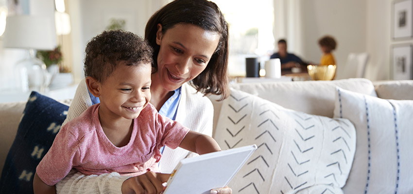 Mom holding son on lap while looking at tablet.