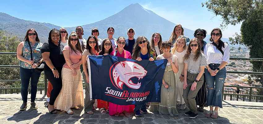 Nurse Practitioner Students in Guatemala holding up South Alabama Jaguars flag.