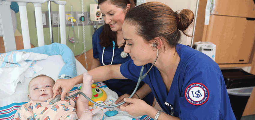 USA Nursing students checking on baby in hospital listening to heartbeat.