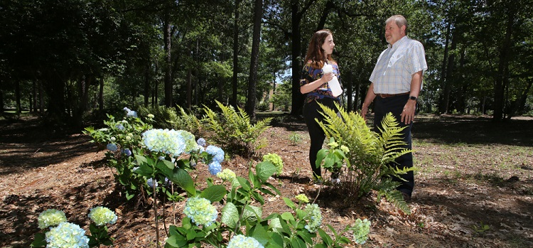 Dr. Kevin White, right, professor and chair of the department of civil, coastal and environmental engineering, and Jordan Blackmon, sophomore civil engineering major, stand on the edge of one of five landscaped bioinfiltration swales near Meisler Hall. The swales help capture storm water runoff instead of it running off on the surface and eroding soil that eventually deposits into Three Mile Creek.