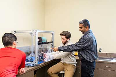 Professor pointing to machine in box.