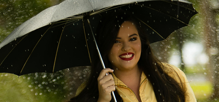 Samantha Michlowicz standing in the rain with a umbrella