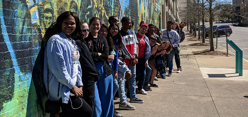 Group of Honors students standing beside grafitti covered wall on trip to Selma and Montgomery