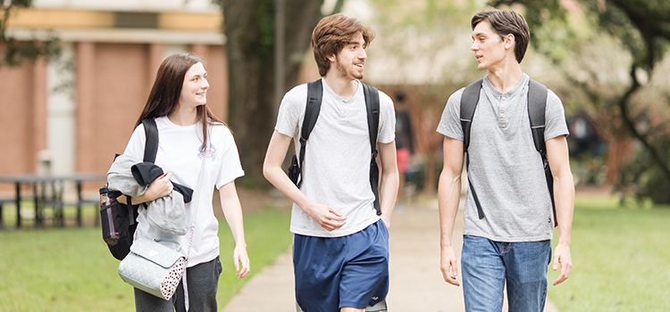 Three students walking on campus.