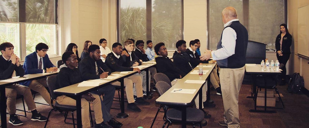 Build-A-Bridge participants listening in a classroom.