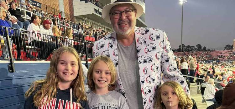 MCOB Professor Dr. Al Chow pictured supporting the Jaguars at the USA vs. Southern Miss game, he's accompanied by the children of MCOB Alumni Brandi Dugger, (left to right) Casadei, Johnny and Julian.