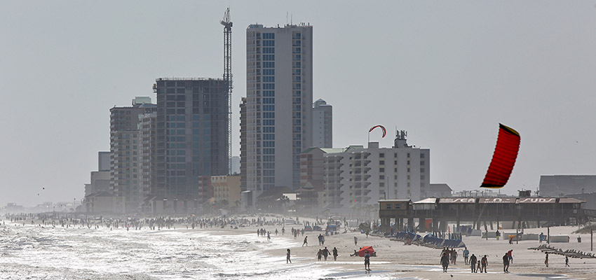 People walking on beach with condos in background.