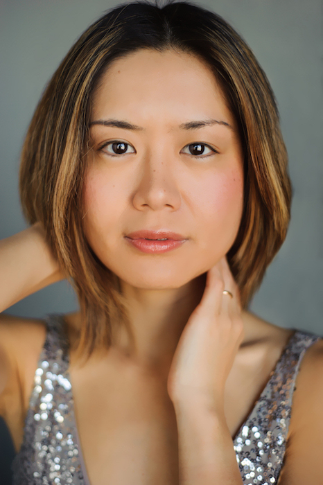 close-up of Jasmin Arakawa posed with one hand positioned on her neck and one behind her head