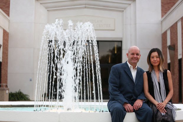 Rudolf Haken and Jasmin Arakawa seated beside fountain in front of Laidlaw Performing Arts