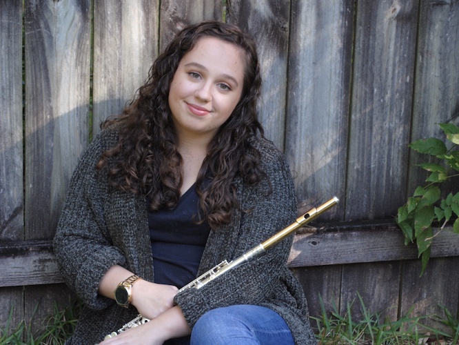 Pictured artistically in her back yard in front of a fence, holding her flute, is Hanna Ardrey. data-lightbox='featured'