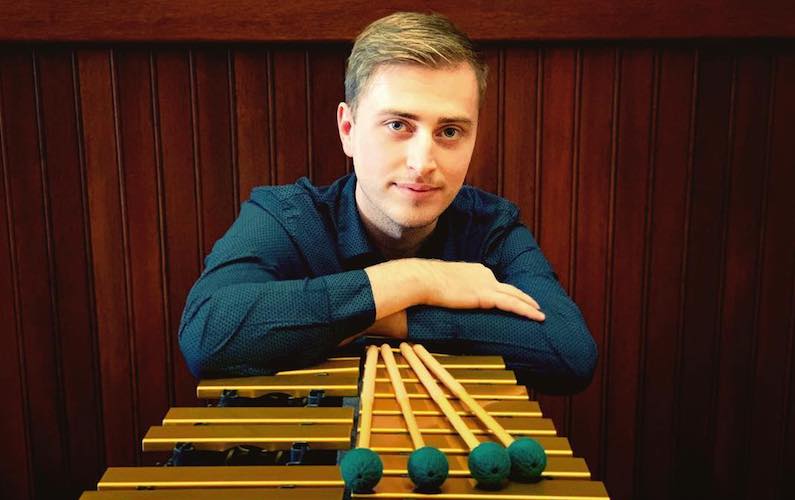 Pictured laterally at the vibraphone with mallets is senior percussionist Brandon Benson.