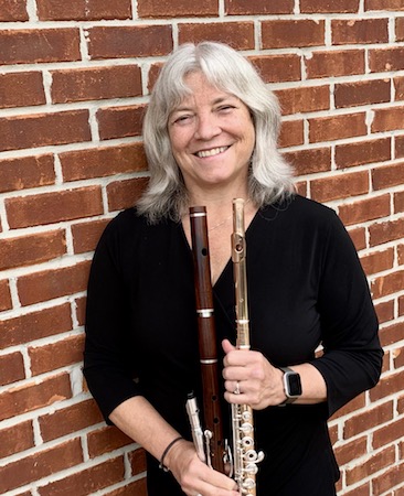Faculty flutist Dr. Andra Bohnet is pictured posing with her flute next to a brick wall at her home. data-lightbox='featured'
