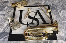 Brass instruments are pictured in an array on the floor of the Laidlaw Performing Arts Center Lobby.