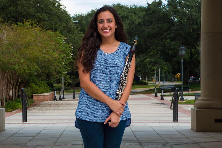 Alexys Bush standing outside in Moulton Plaza with Clarinet